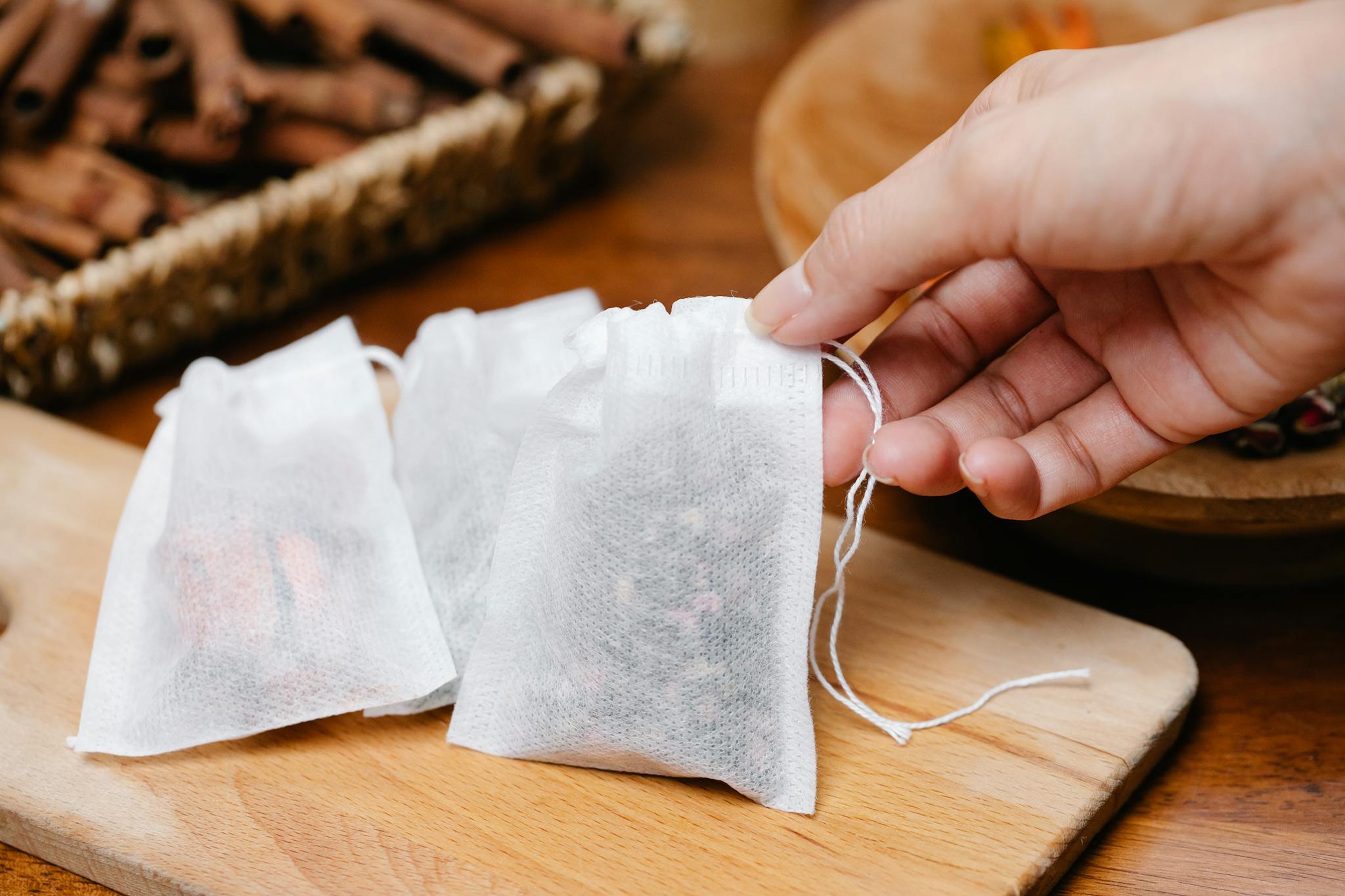 A close-up shot of a hand holding a herbal tea bag, surrounded by ingredients.